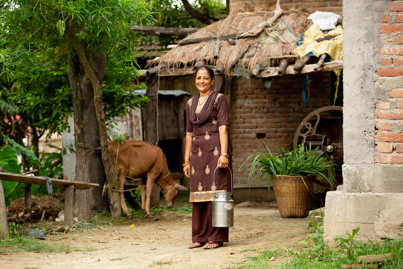 Femaile dairy farmer wearing a sari and holding a milk pail